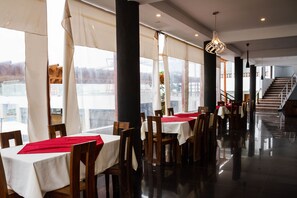 A restaurant with tables set for dining, large windows, and a staircase in the background. - Qallwa Chincha (Sunampe)