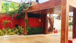 A hotel entrance with a red wall, a wooden gate, and a sign indicating a parking area. - Qallwa Chincha (Sunampe)