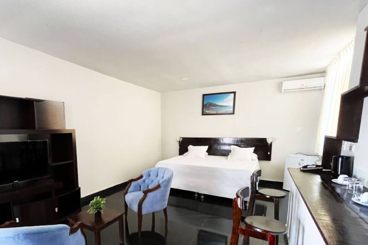 A hotel room with a bed, a TV, a desk, and two chairs.