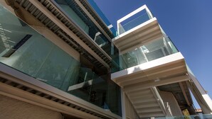 A modern building with multiple glass balconies and a clear blue sky. - Apartamentos Datasol (San Bartolomé de Tirajana)