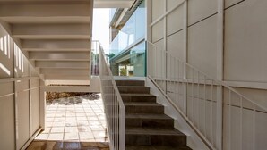 A modern staircase with a glass railing leading to an outdoor area with a stone floor. - Apartamentos Datasol (San Bartolomé de Tirajana)