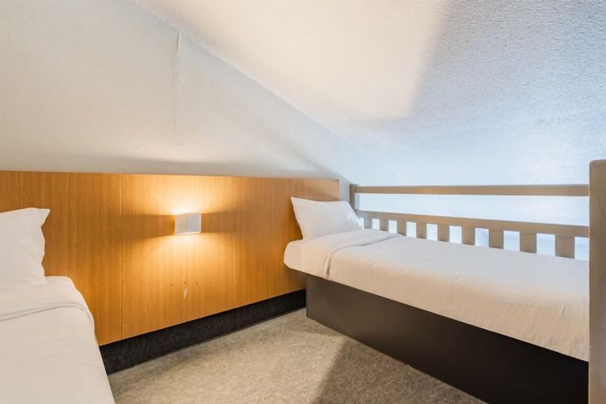 Un dormitorio pequeño y acogedor con cabecera de madera, una cama individual y una mesita de noche.