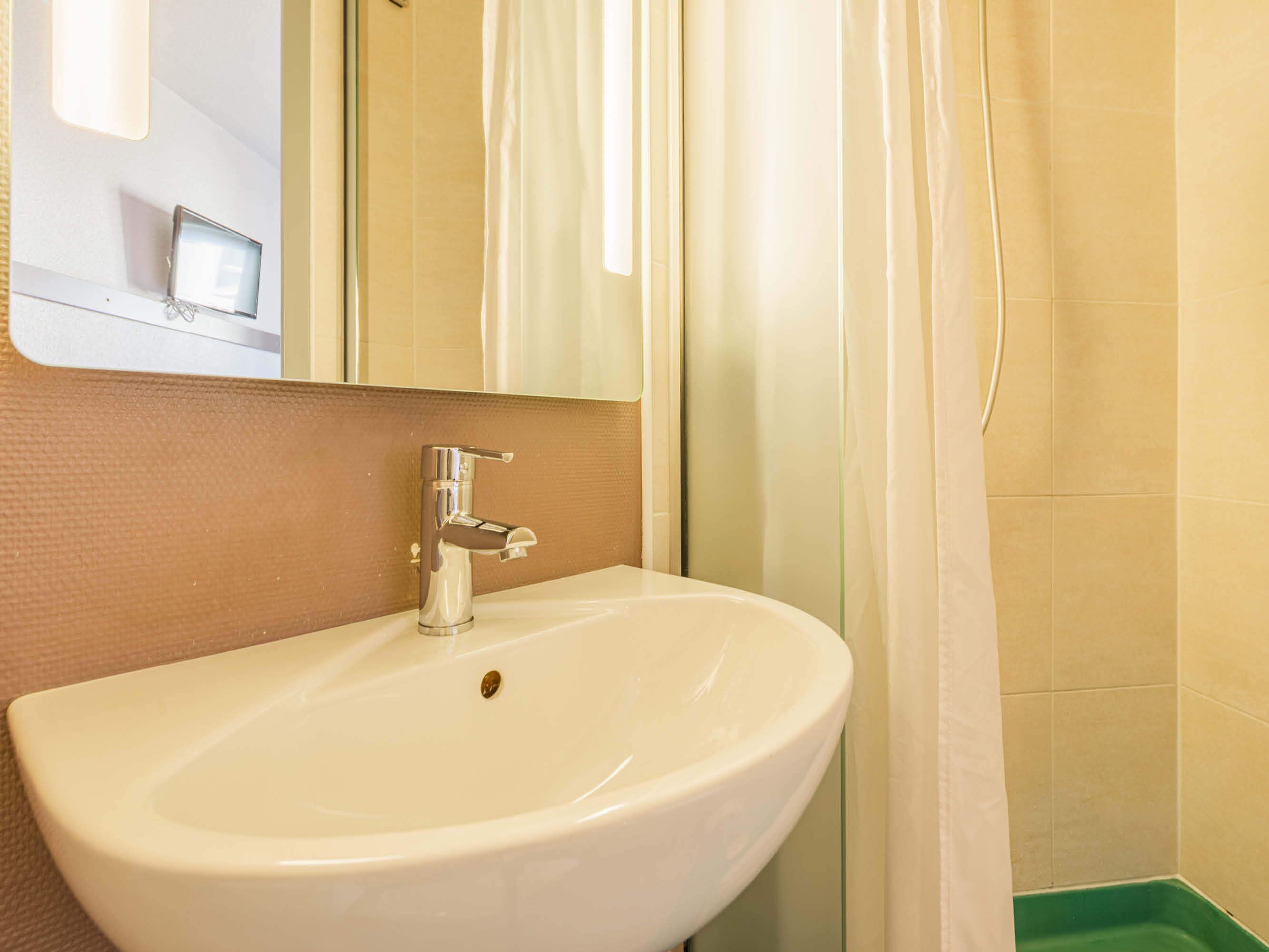 Ein Badezimmer mit einem weißen Waschbecken, einem Spiegel und einer Duschvorhang.