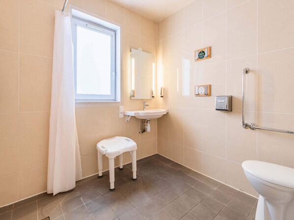 Un baño con inodoro, lavabo y un taburete pequeño.