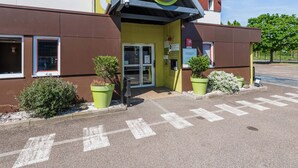 A B&B hotel with a yellow facade, a brown entrance, and green planters. - B&B HOTEL Strasbourg Sud Ostwald (Ostwald)