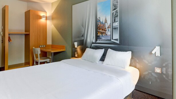 A hotel room with a large bed, a desk, and a chair. - B&B HOTEL Beaune Sud (2) (Beaune)