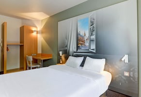 Una habitación de hotel con una cama grande, un escritorio y una silla.