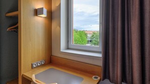A small bathroom with a window, a wooden cabinet, and a sink. - B&B HOTEL Beaune Sud (2) (Beaune)