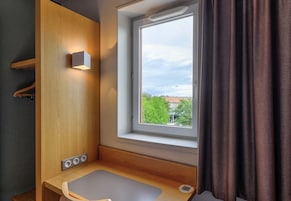 Un baño pequeño con ventana, un mueble de madera y un lavamanos.