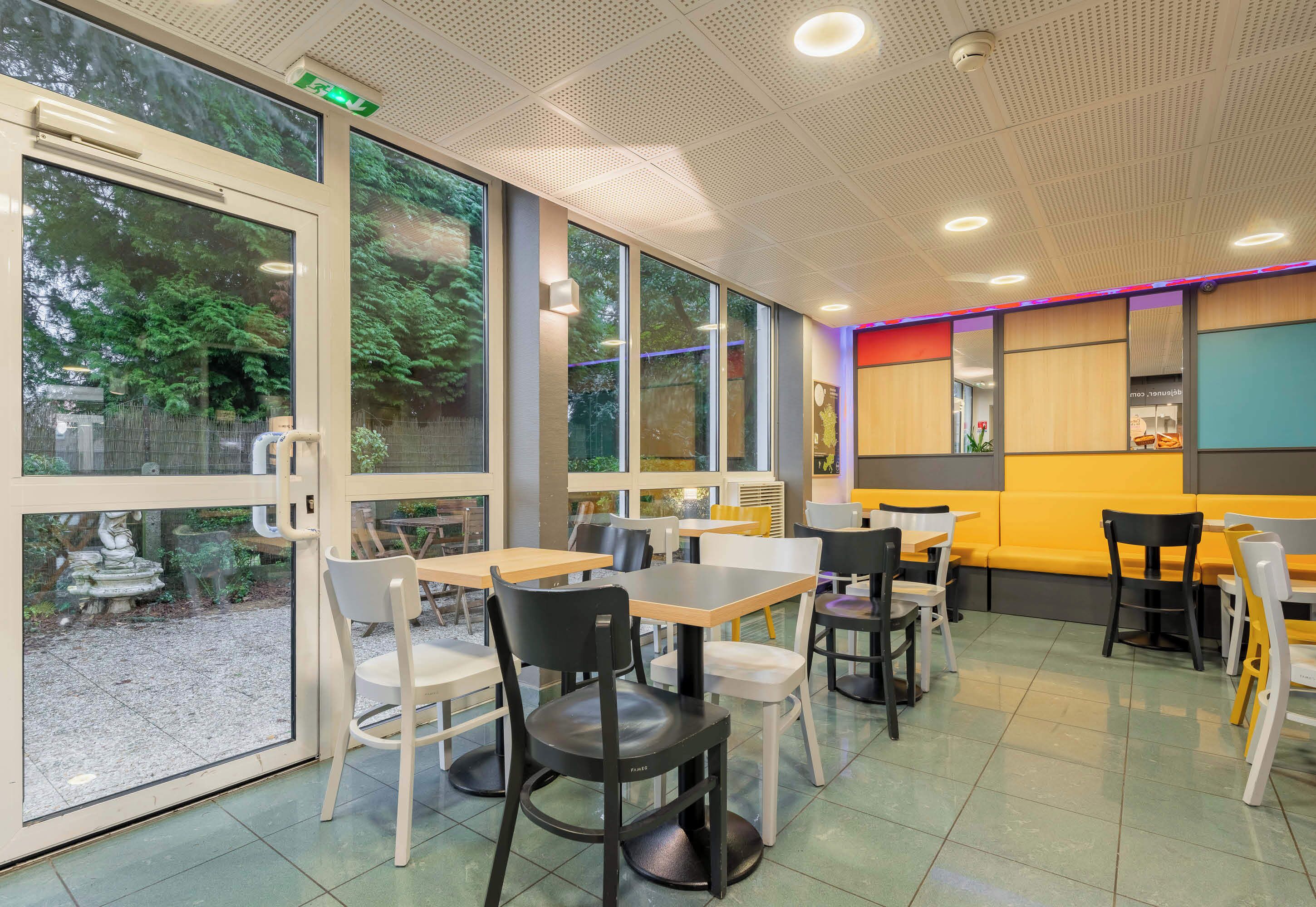 Un interior de restaurante con ventanas amplias, asientos dentro y una combinación de mesas y cabinas.