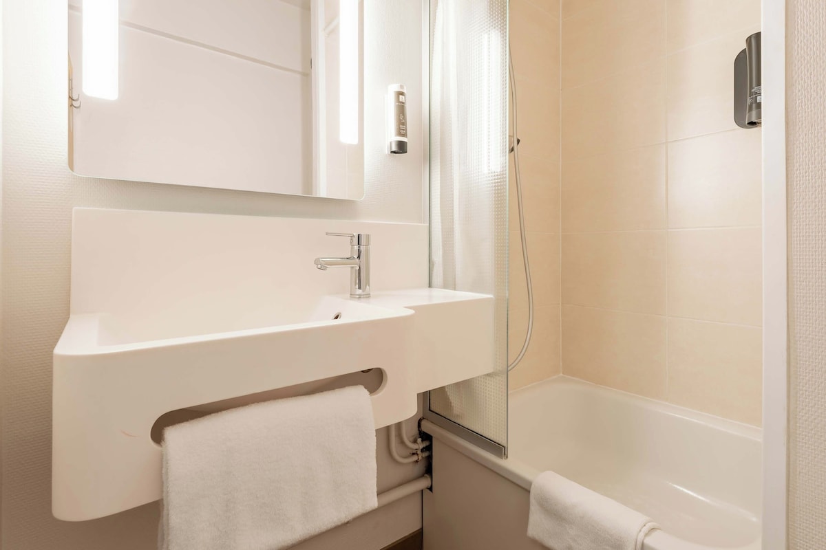A modern bathroom with a white sink, mirror, and bathtub.