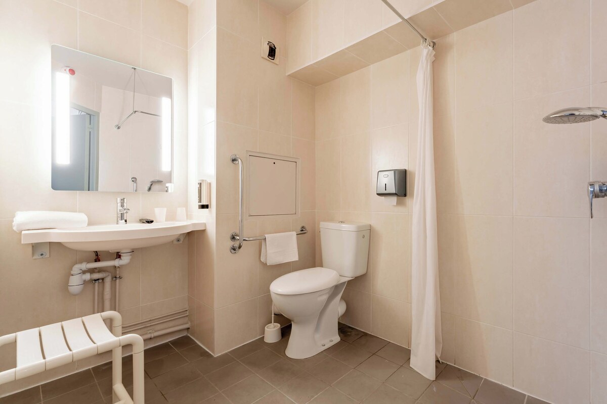 A modern bathroom with a sink, toilet, shower, and a mirror.