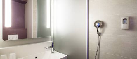 A modern bathroom with a white sink, a mirror, and a handheld showerhead.