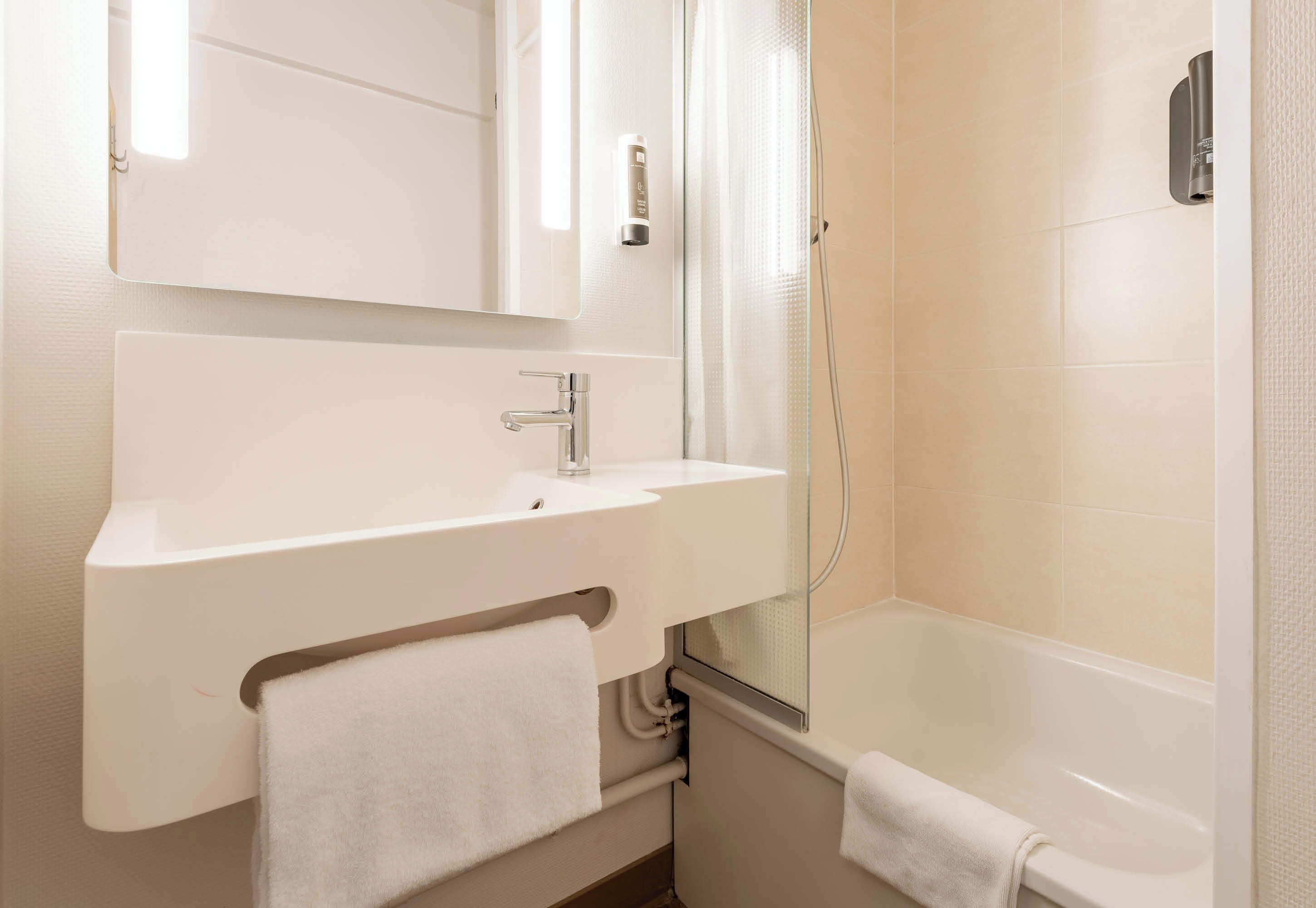 A modern bathroom with a white sink, mirror, and bathtub.
