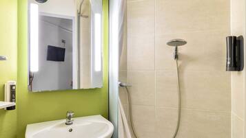 A bathroom with a sink, mirror, and shower.