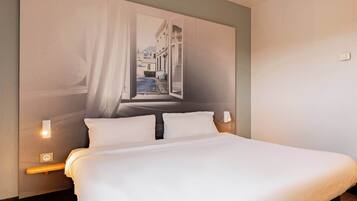 A neatly made bed with white linens, a headboard with a cityscape mural, and bedside lamps.