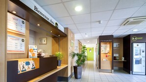 Una zona de recepción con un mostrador de madera, un cartel de B&B, una tienda de B&B y una planta.