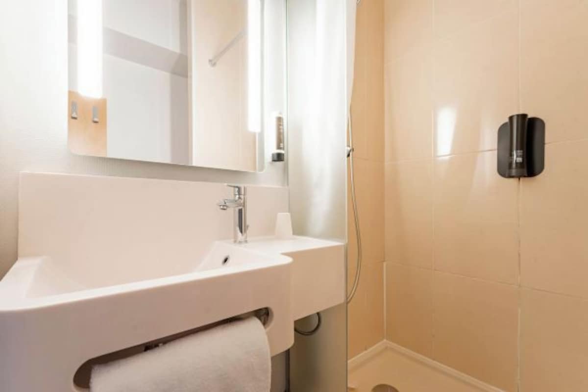 Een moderne badkamer met een witte wastafel, spiegel en handdoekhouder.