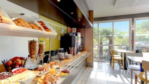 Un bufé de desayuno con diversas opciones de comida y una zona de estar con mesas y sillas.