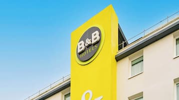 A B&B hotel sign on a yellow building with a clear blue sky in the background.