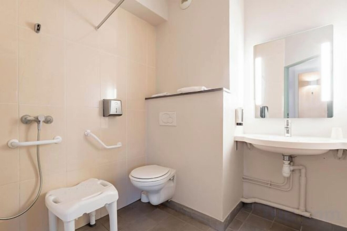 Un baño con inodoro, lavamanos, espejo y zona de ducha.
