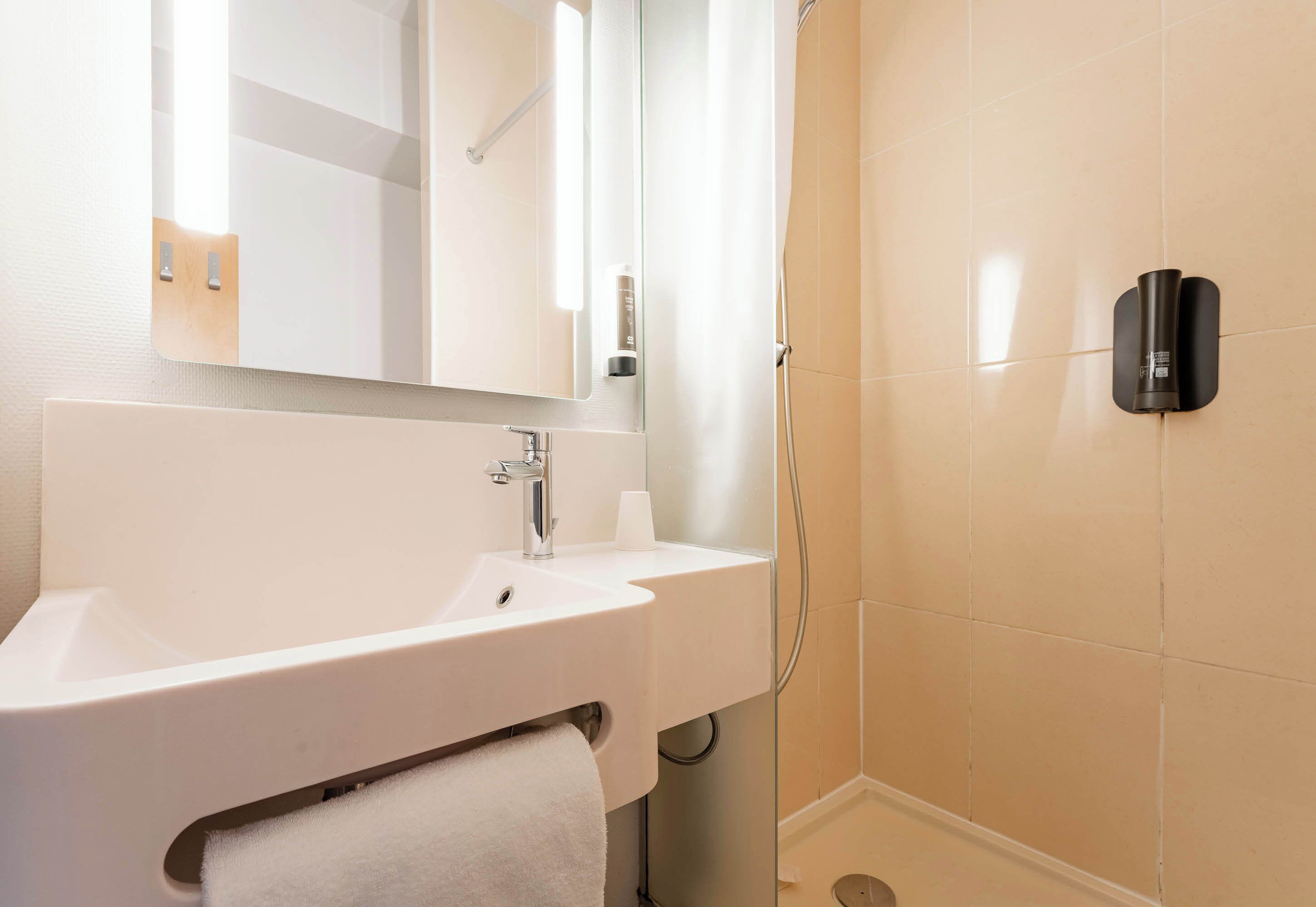 Un baño con lavamanos blanco, espejo y ducha.