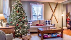 A cozy living room with a Christmas tree, a sofa, a coffee table, and a fireplace.