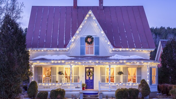 A house with a red roof, a porch with white railings, and a blue door.