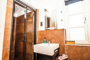 A bathroom with a glass shower enclosure, a white sink, and a mirror above it. - Elgano Guest House (Cardiff)