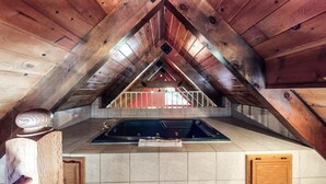 A wooden attic space with a kitchen area, including a sink and countertop.