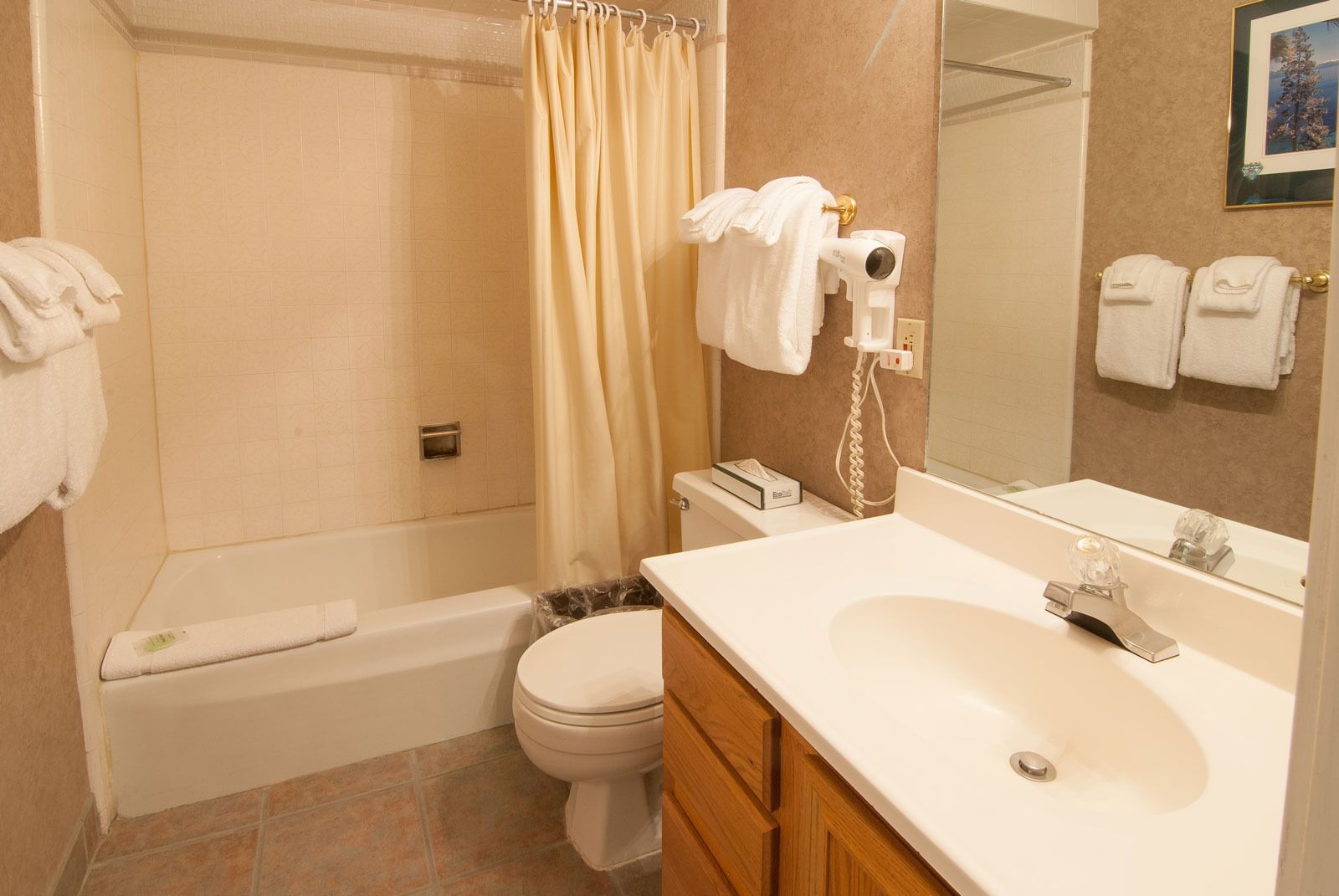 Une salle de bain avec une baignoire, des toilettes et un lavabo. On y trouve un rideau de douche, un porte-serviettes et un miroir.