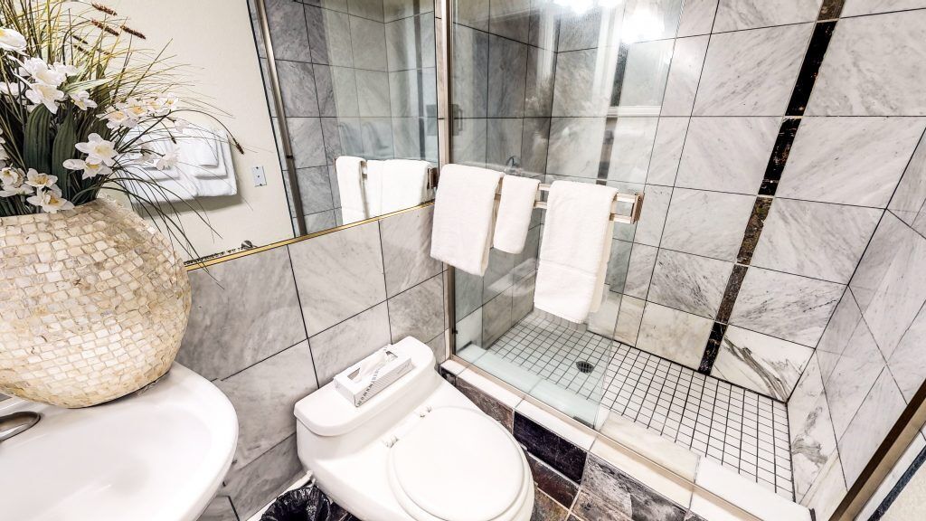 A modern bathroom with a shower, toilet, and sink.