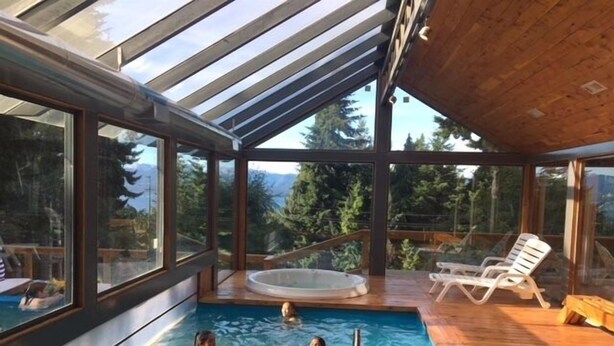 An indoor swimming pool with clear views of the surrounding forest and mountains through large windows. - Residencia Pioneros (San Carlos de Bariloche)