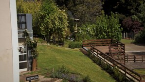 A reception area with a wooden deck, a sign reading "RECEPCIÓN", and a building with a glass door. - Residencia Pioneros (San Carlos de Bariloche)