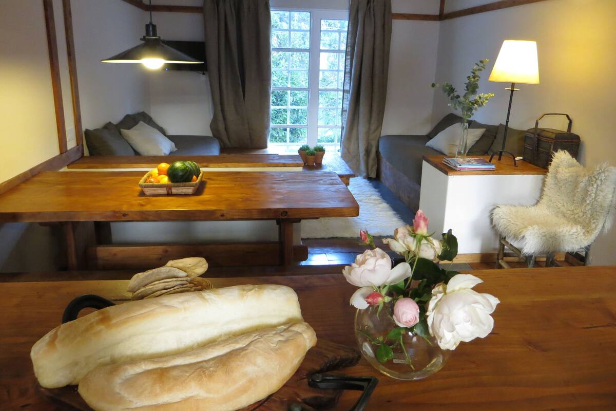 A dining area with a wooden table, benches, and a vase with flowers.