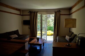 Uma sala de estar aconchegante com sofá, mesa de madeira, luminária e televisão na parede.
