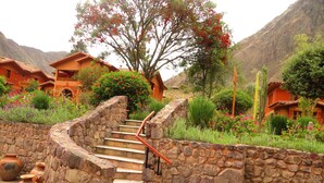 A stone staircase leading to a building surrounded by lush gardens and a mountainous backdrop. - Hotel Pakaritampu (Ollantaytambo)