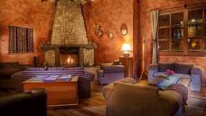 A cozy living room with a stone fireplace, wooden beams, and comfortable seating. - Hotel Pakaritampu (Ollantaytambo)