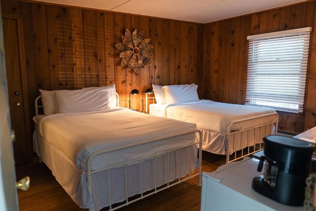 A room with two beds, a coffee maker, and a wall decoration.