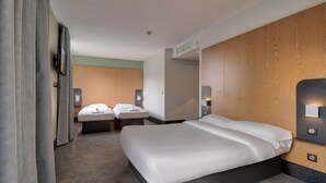 A modern hotel room with a large bed, bedside tables, a mirror, and a wooden accent wall.