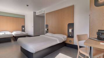 Et moderne hotelværelse med en stor seng, to sengeborde, et skrivebord med en bærbar computer og en stol.