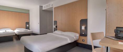 A modern hotel room with a large bed, two bedside tables, a desk with a laptop, and a chair.