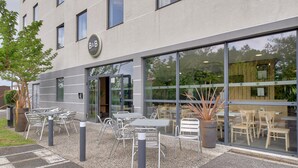 A B&B hotel exterior with outdoor seating, large windows, and a modern design.