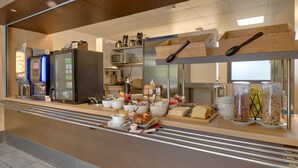 A modern breakfast bar with a variety of food items, including pastries, fruits, and beverages.