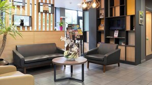 A reception area with a sofa, chairs, a round table, and a potted plant.