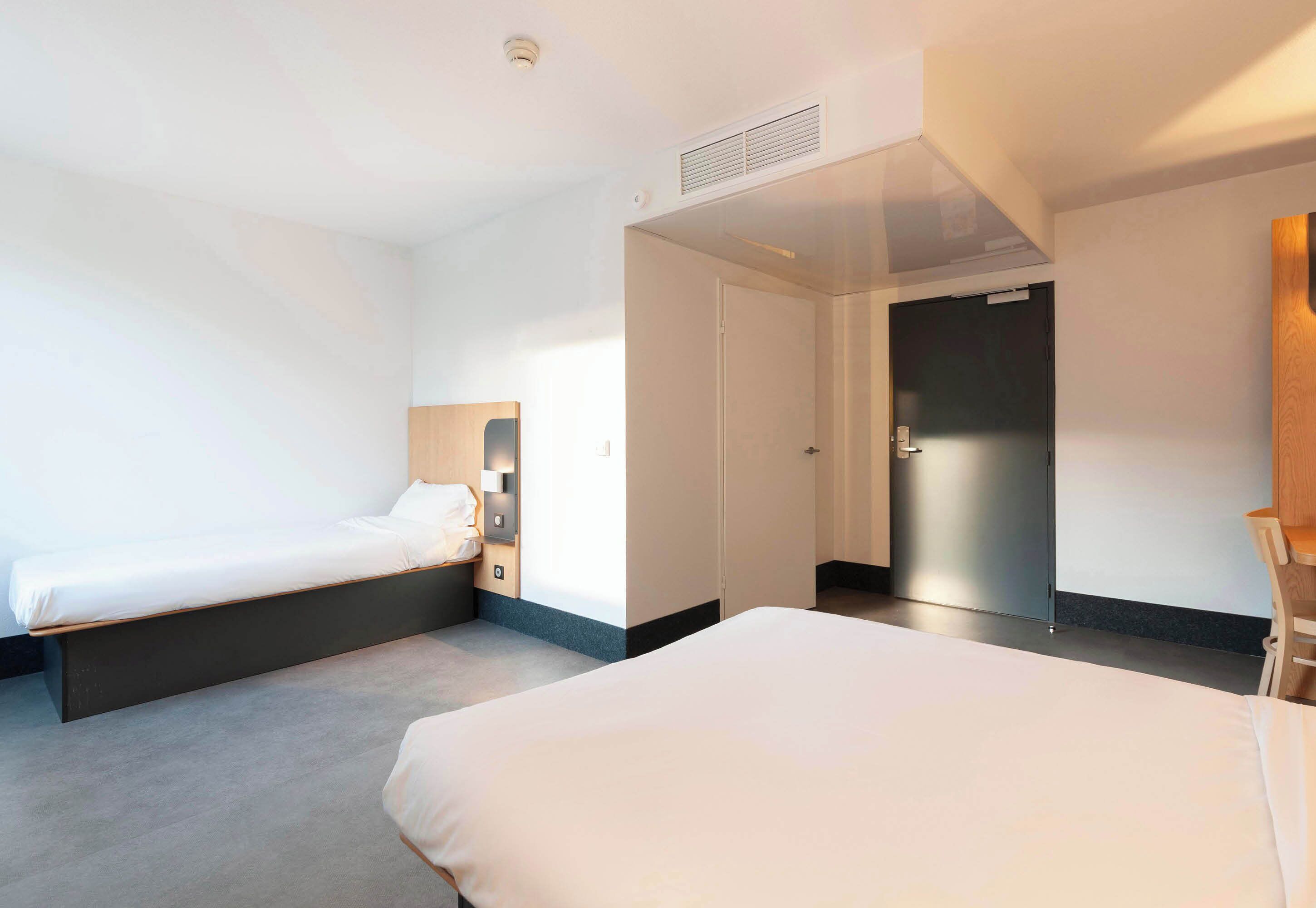 Una habitación de hotel con dos camas, un armario y un escritorio.