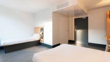 Una habitación de hotel con dos camas, un armario y un escritorio.