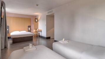 Una habitación de hotel moderna con una cama grande, una cama más pequeña, un escritorio y una silla.