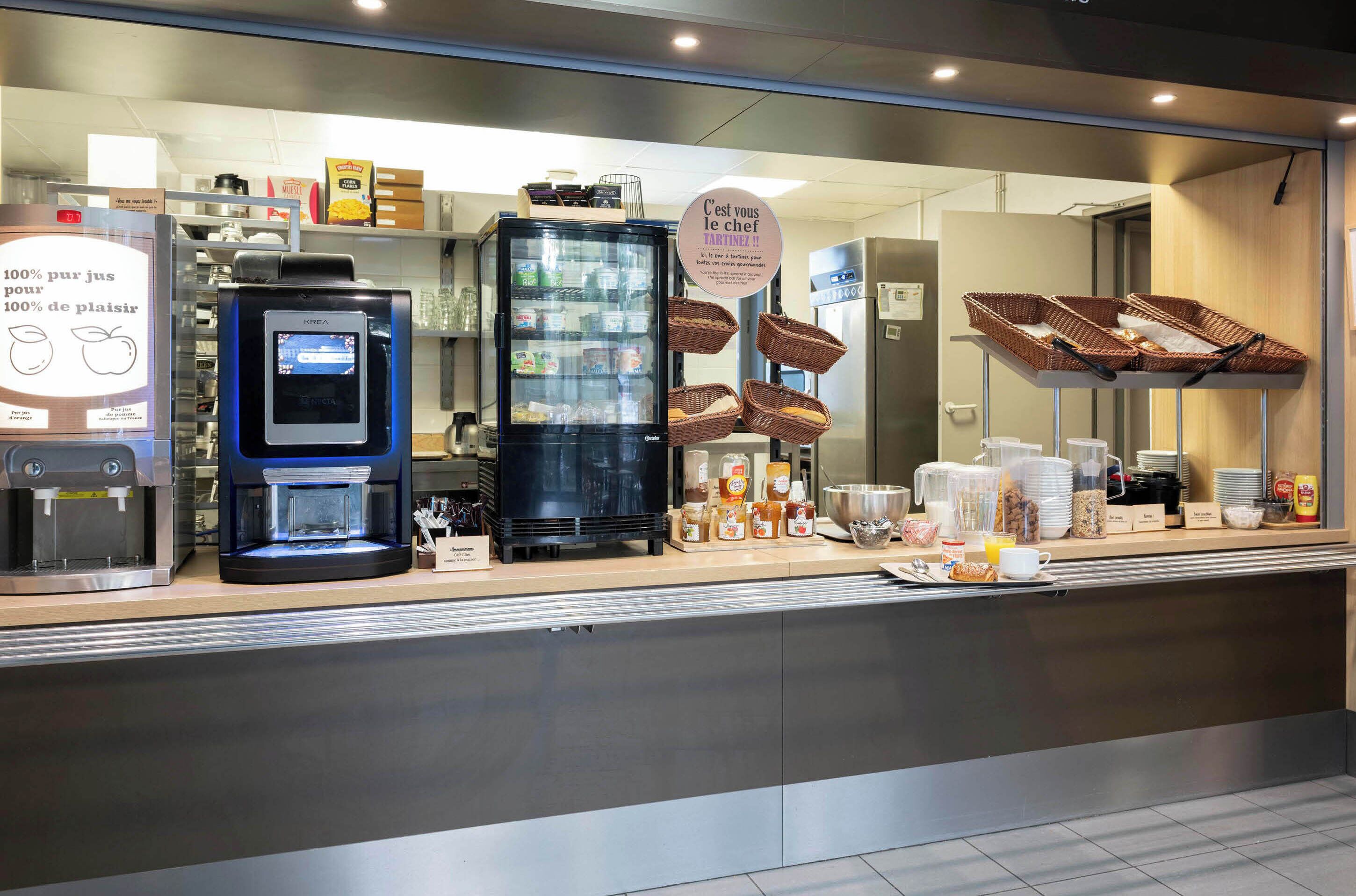 Un café moderno con una máquina de café, vitrina refrigerada y diversas opciones de comida.