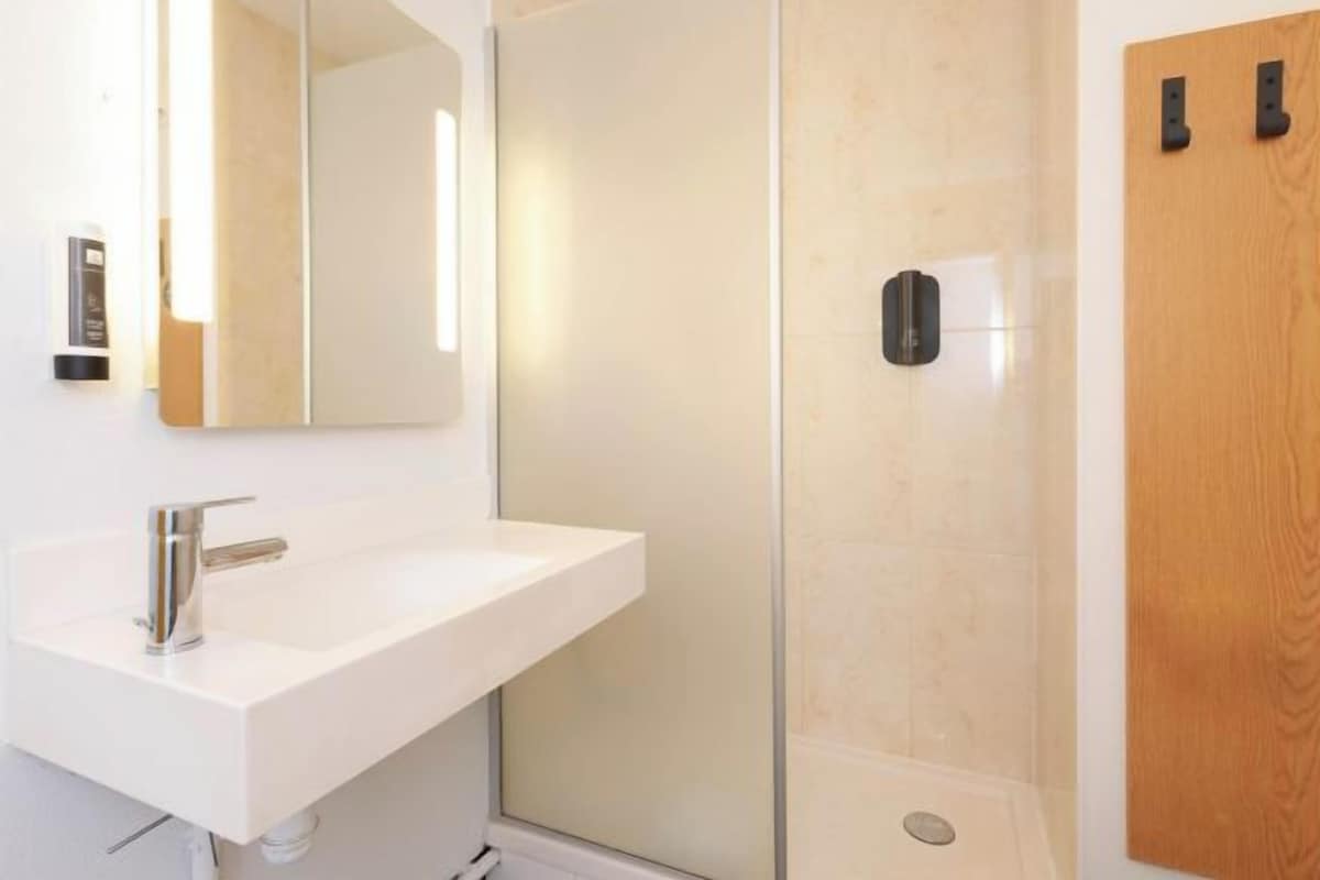 A modern bathroom with a white sink, a mirror, and a glass shower enclosure.
